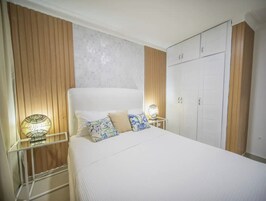 Un dormitorio con cama, mesitas de noche, armario y pared con textura.
