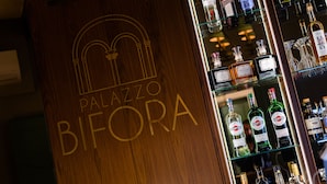 A wooden bar counter with the name "Palazzo Bifora" and a variety of liquor bottles. - Palazzo Bifora (Mdina)
