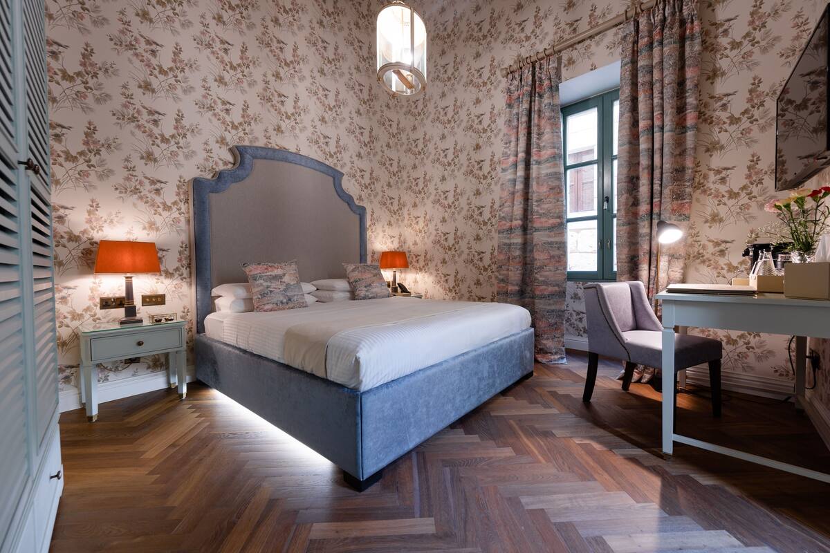 Un dormitorio con una cama grande, dos mesitas de noche, un escritorio y una silla.