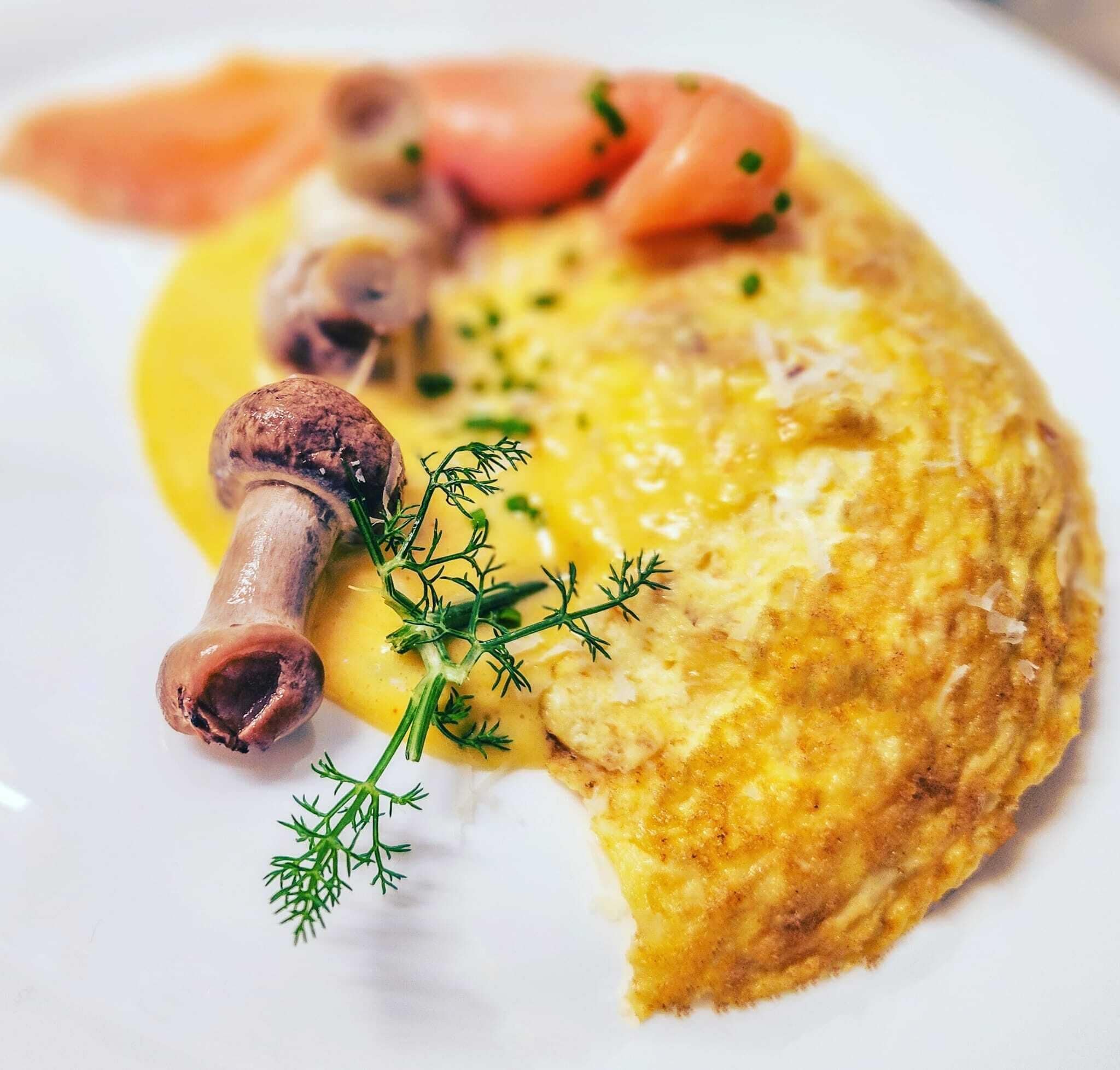 A plate with an omelette, salmon, mushrooms, and dill garnish.