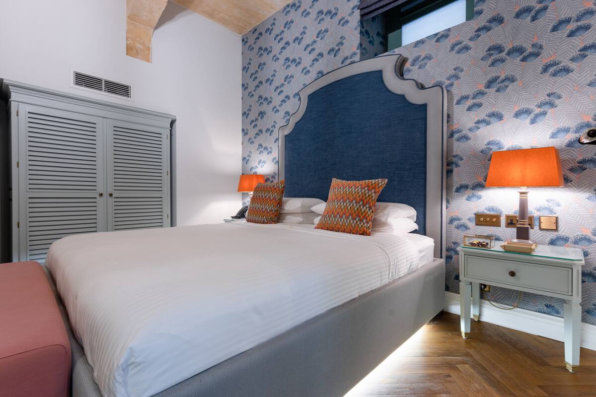 Un dormitorio con una cama grande, dos lámparas de noche, una mesita de noche y un armario.