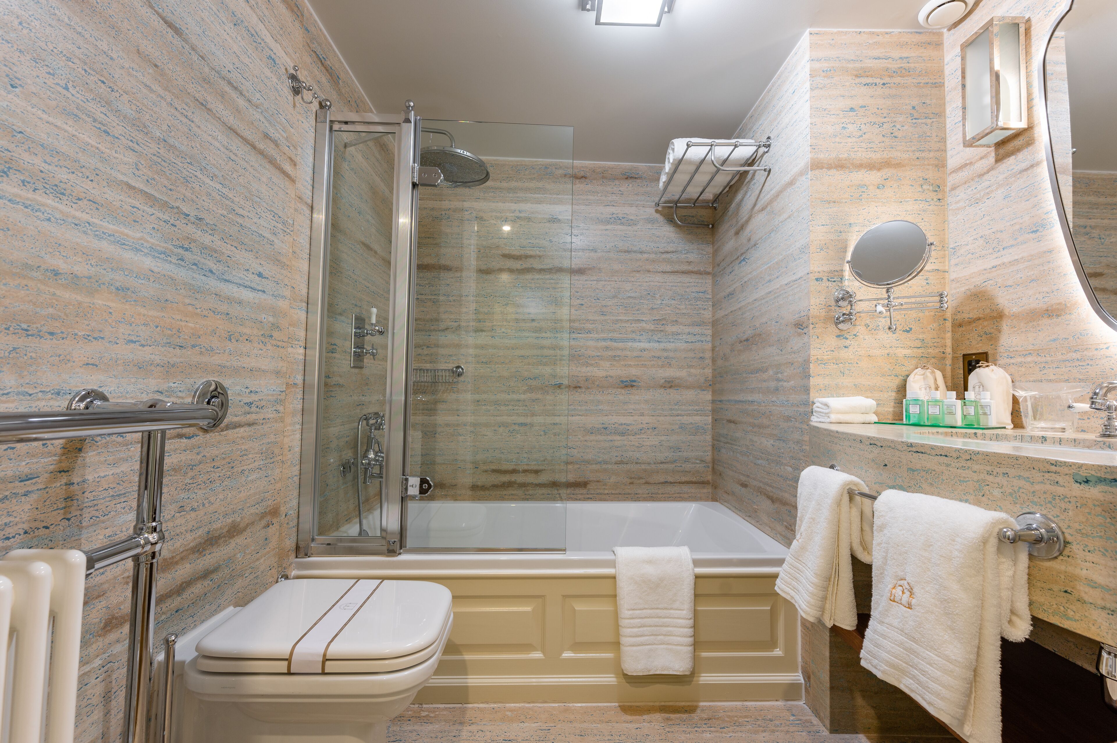 A bathroom with a glass-enclosed shower, a bathtub, a toilet, and a vanity with a mirror and towel rack.