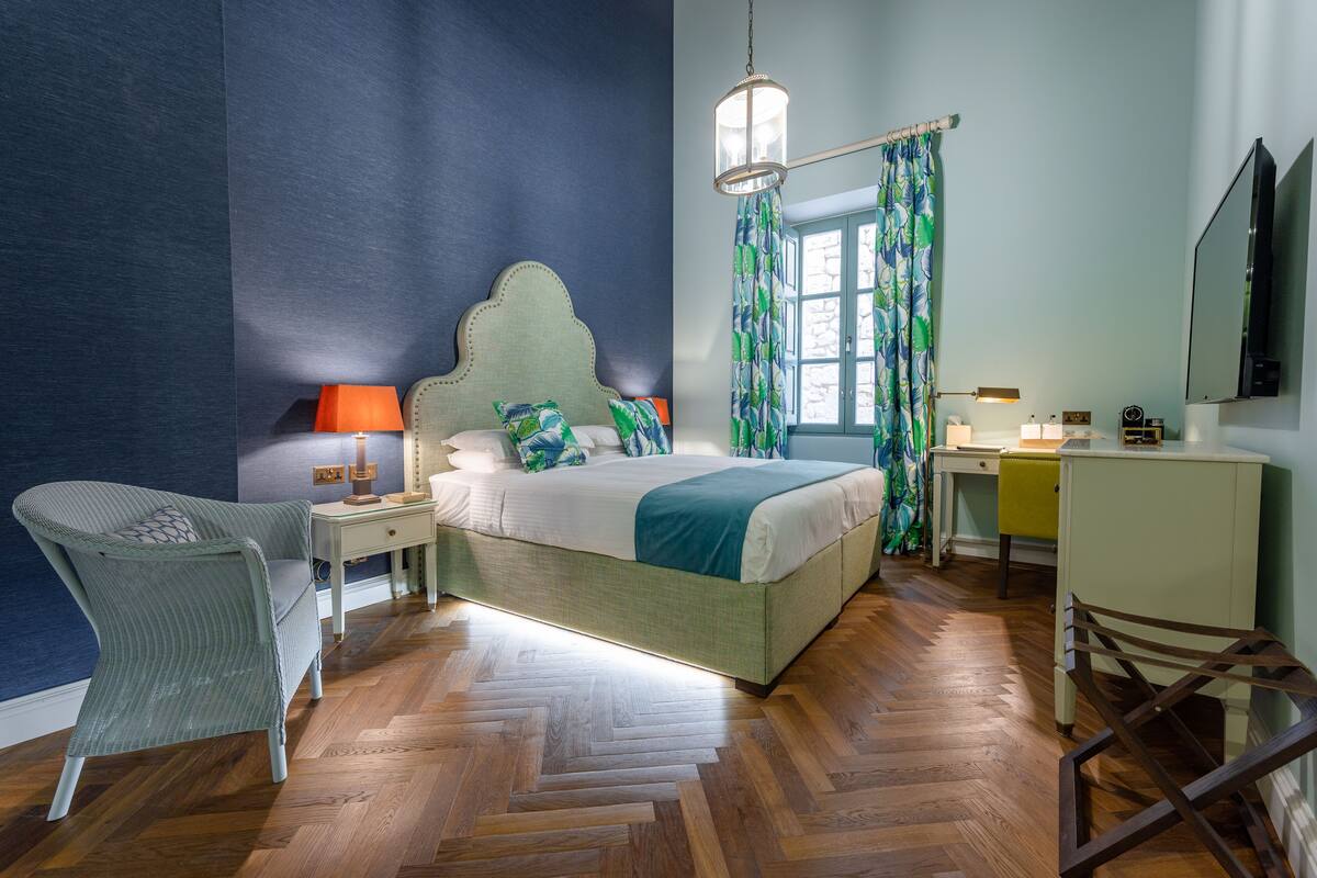 Un dormitorio con cama, una silla, un escritorio y un espejo.