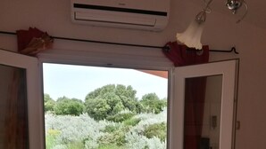 Puerta corredera abierta que da a un patio exterior con una mesa y sillas, un ventilador de techo y un equipo de aire acondicionado.