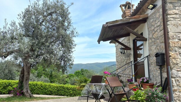 A stone building with a gravel patio, outdoor seating, and potted plants.