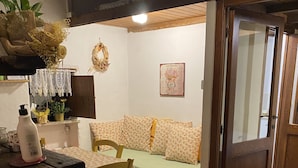 A cozy room with a green sofa, a wooden table with a bottle, and a potted plant.