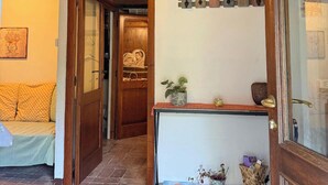 A cozy room with a wooden ceiling, a bed with yellow checkered bedding, a wooden console table with a plant, and a 'Welcome' sign.