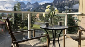 A balcony with a table, chairs, and a vase of flowers.