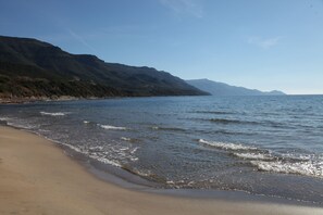 A beach with a clear view of the ocean and distant mountains.
