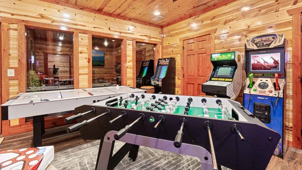Un intérieur en bois agr émenté d’un baby-foot, de deux jeux d’arcade et d’une table de billard.