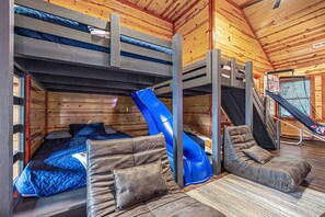 A cabin with bunk beds, a blue slide, a small staircase, and a window. - Heated In-Cabin Pool~Theatre~Game Room~Views (Sevierville)