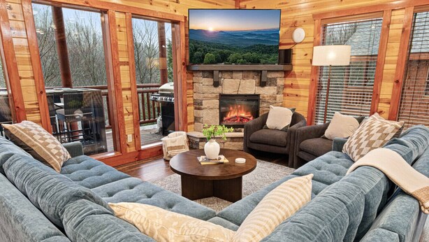 A cozy living room with a stone fireplace, a large flat-screen TV, and a comfortable seating area. - Heated In-Cabin Pool~Theatre~Game Room~Views (Sevierville)