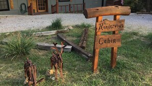 Un letrero de madera que dice "Rendezvous Cabin", situado frente a un edificio con techo de metal y una puerta de garaje.