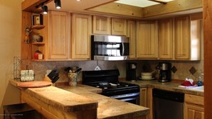 Una cocina con armarios de madera, un microondas de acero inoxidable y una estufa negra.