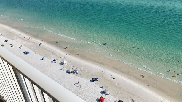 A beach with clear turquoise water, a sandy shore, and several beach umbrellas. - LUXURY 20TH FLOOR BEACHFRONT CONDO/HUGE BALCONY/BEACH SERVICE/5 STAR REVIEWS (Panama City Beach)