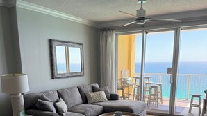 A living room with a gray sectional sofa, a coffee table, a side table, and a view of the ocean through large sliding glass doors. - LUXURY 20TH FLOOR BEACHFRONT CONDO/HUGE BALCONY/BEACH SERVICE/5 STAR REVIEWS (Panama City Beach)