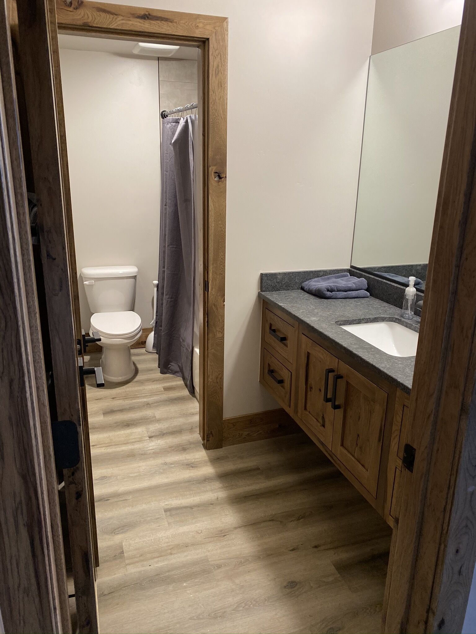 A bathroom with a wooden vanity, a sink, and a toilet.