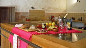 A kitchen counter with various food items, a bottle of champagne, and a red placemat. - Facing the valley, in Ste Jalle, gîte equipped for 4 (Sainte-Jalle)