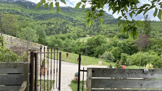 A wooden gate leading to a stone pathway with a mountainous backdrop. - Facing the valley, in Ste Jalle, gîte equipped for 4 (Sainte-Jalle)