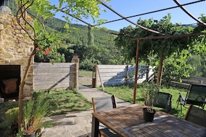 A patio with a table and chairs, a stone wall, and a wooden fence. - Facing the valley, in Ste Jalle, gîte equipped for 4 (Sainte-Jalle)
