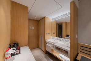 Un baño moderno con tocador de madera, un espejo grande y encimera blanca.