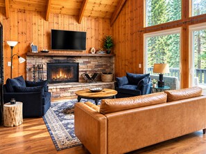 A cozy living room with a fireplace, leather sofa, and a large window.