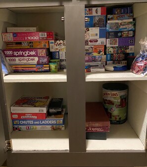 A shelf with various board games and puzzles, including 'Springbok' and 'Scrabble'. - Cozy Escape- Walking Distance to Village! (Lake Arrowhead)