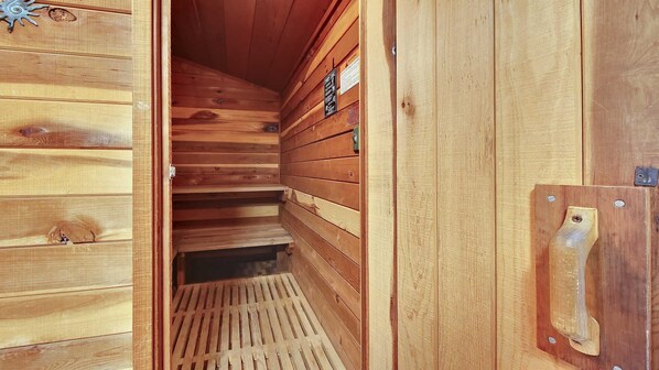 L’intérieur d’une cabane en bois, avec un plafond en pente, une porte en bois dotée d’une poignée et une petite grille d’aération sur le mur.