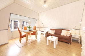 En rummelig opholdsstue med et spisebord, en brun sofa og et hvidt sofabord.