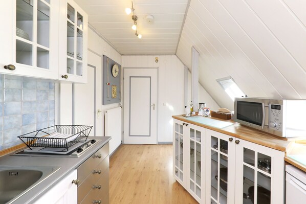 Una cocina con armarios blancos, microondas, fregadero y encimera de madera.