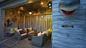 A cozy, nautical-themed lounge area with wicker furniture, a clock, and decorative fish.