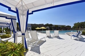 Ein Poolbereich mit weißen Liegestühlen, einem Pool und Sonnenschirmen.