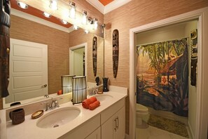 Ein Badezimmer mit großem Spiegel, Waschbecken, Toilette und Duschbereich.