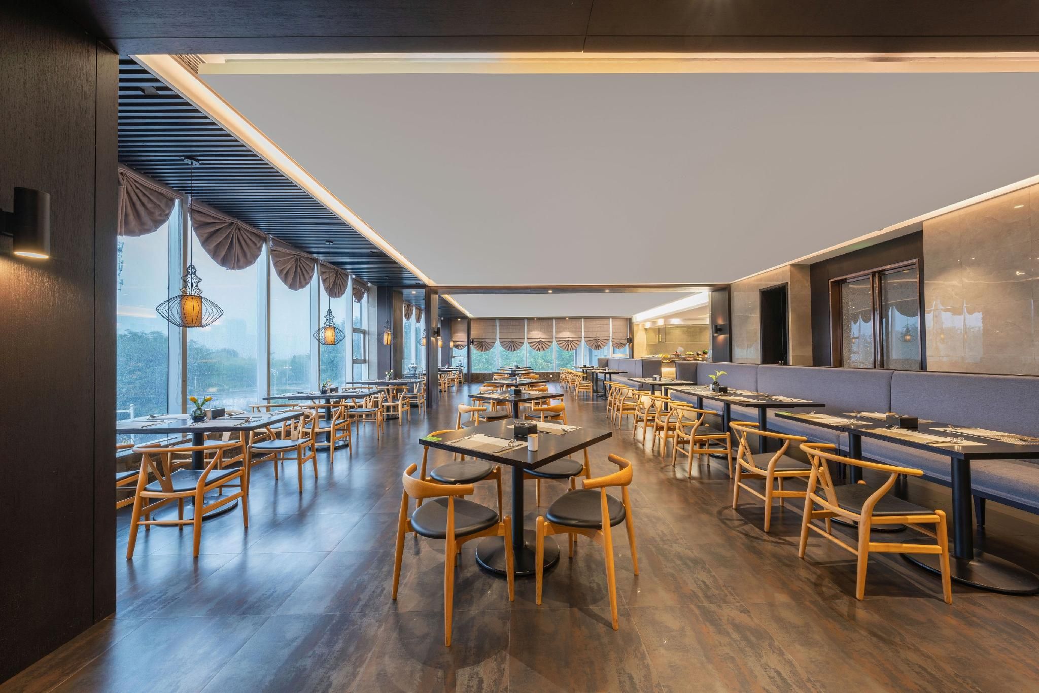 A restaurant with wooden tables and chairs, large windows, and a view of the outdoors.