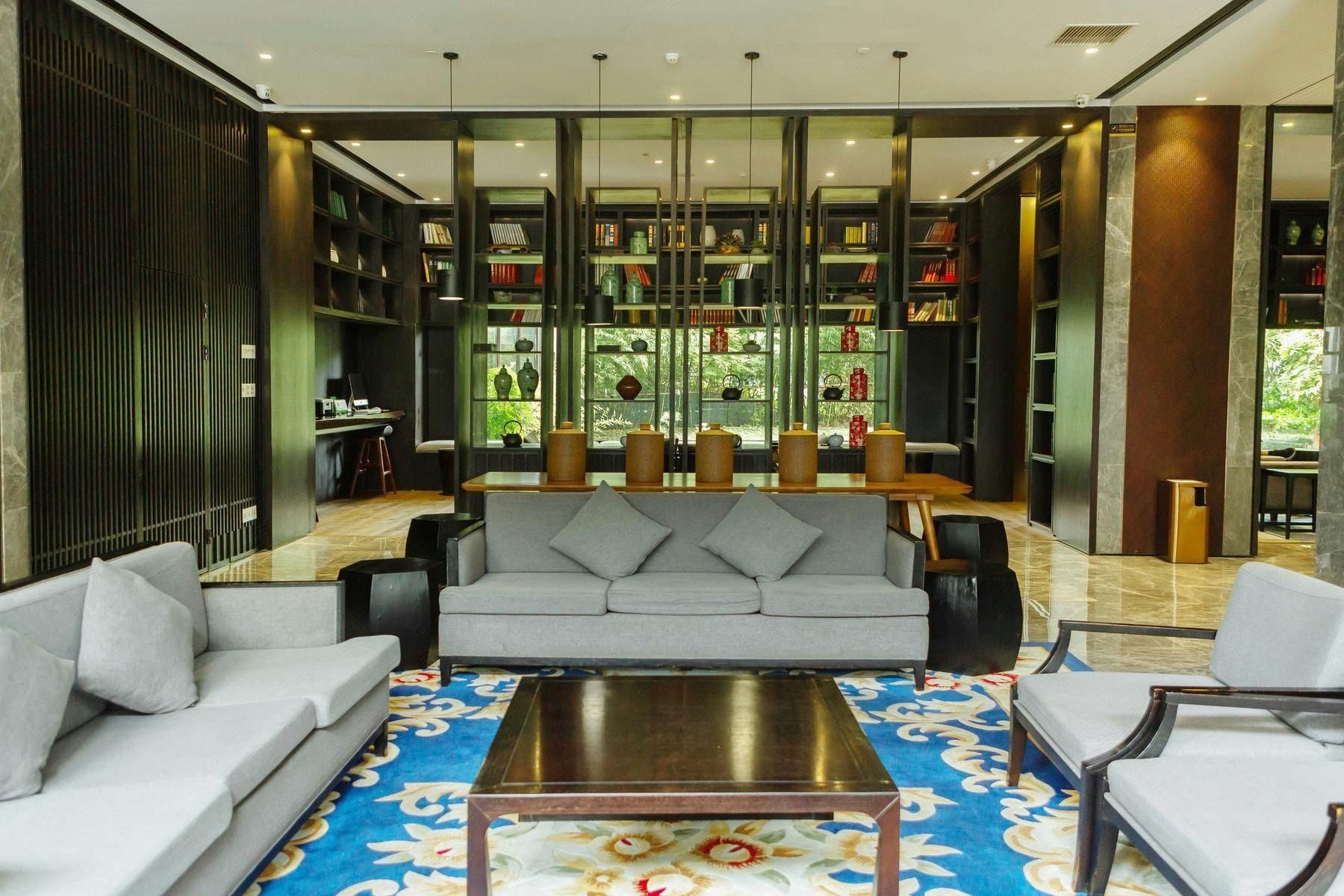 A modern lounge area with a grey sofa, a wooden coffee table, and a patterned rug.