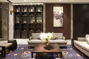 A modern lounge area with a sofa, armchairs, a coffee table, and a decorative vase with flowers.