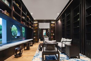 A library with bookshelves, a sofa, a coffee table, and a large window. - Yitel Linyi Binhe Avenue (Linyi)