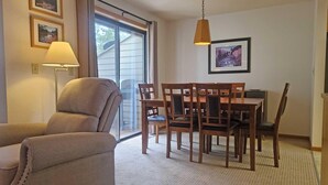 Un salon comprenant un canapé, une table à manger, des chaises, une lampe et un tableau accroché au mur.