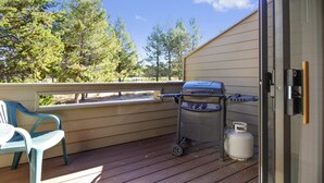 Une terrasse avec un barbecue, une bouteille de gaz et une chaise.