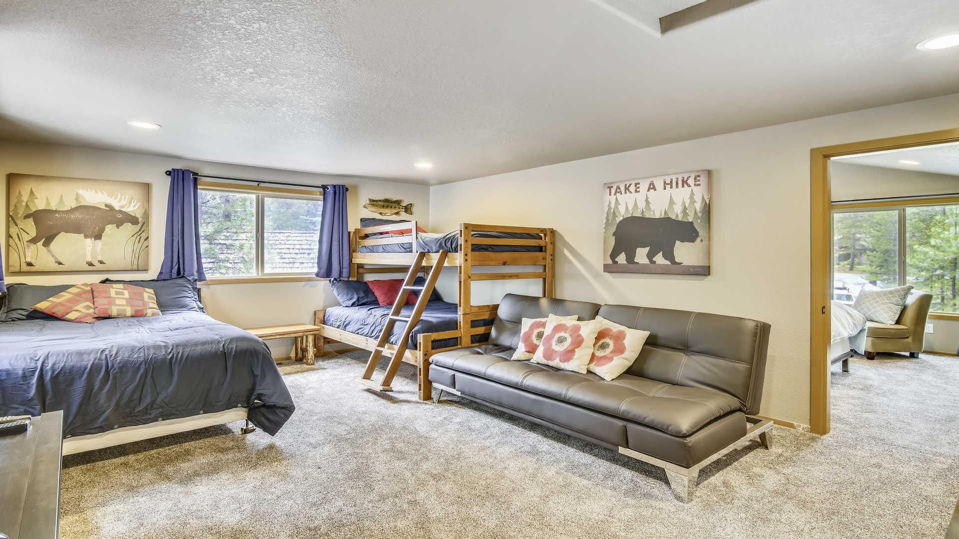 A cozy room with a bunk bed, a sofa, a ladder, and a motivational poster.