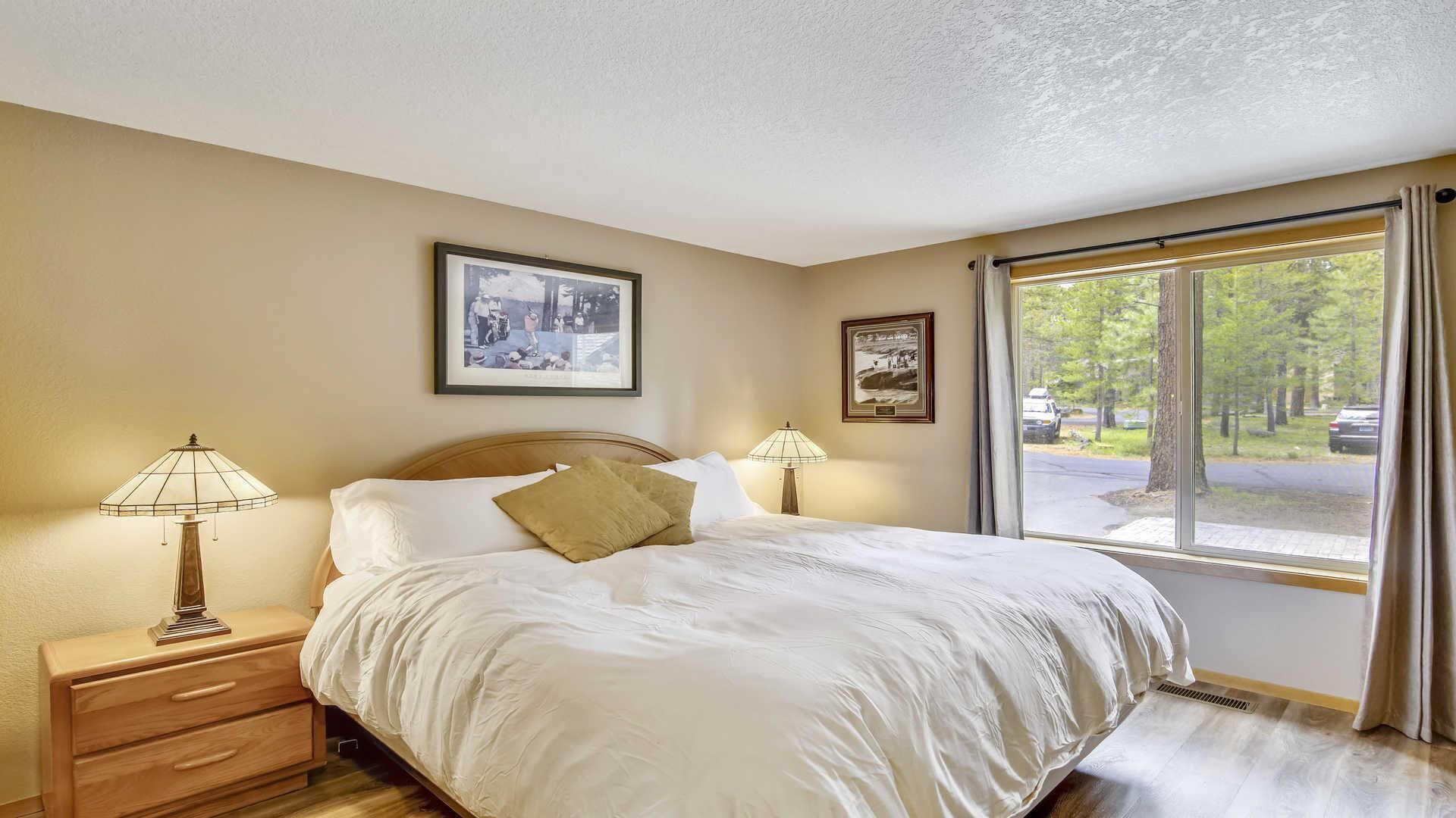 A bedroom with a large bed, two bedside lamps, and two framed pictures on the wall.