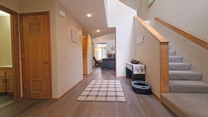 A hallway with a wooden door, a rug, a staircase, and a dining area in the background. - Skyline Condo 02 (Bend)
