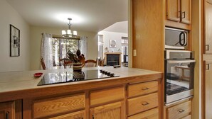 A kitchen with wooden cabinets, a central island with a glass top, and a built-in oven. - Skyline Condo 02 (Bend)