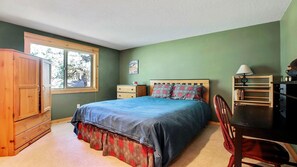 A bedroom with a bed, wooden wardrobe, desk, chair, and a window with a view of trees. - Quail 5 (Bend)