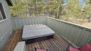 Eine überdachte Terrasse im Freien mit integriertem Sitzplatz und kleinem Tisch, umgeben von einer Holzterrasse und Blick auf Bäume.