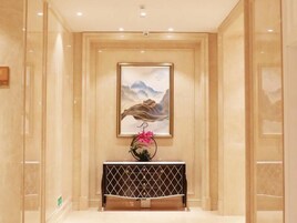 A hallway with a framed artwork on the wall, a console table with a geometric pattern, and a pink flower arrangement.