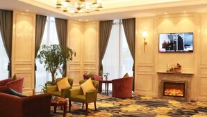 A hotel lobby with a fireplace, comfortable seating, and a large window. - Greentree Eastern Yancheng Binhai County Aobaolia Beichen Hotel (Yancheng)