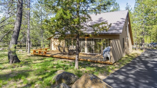 Eine Hütte mit einer Terrasse, Sitzgelegenheiten im Freien und einem überdachten Bereich.