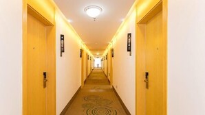 A hotel hallway with doors on both sides, numbered signs above each door, and a carpet with circular patterns. - Greentree Inn Qufu High Speed Railway Station (Jining)
