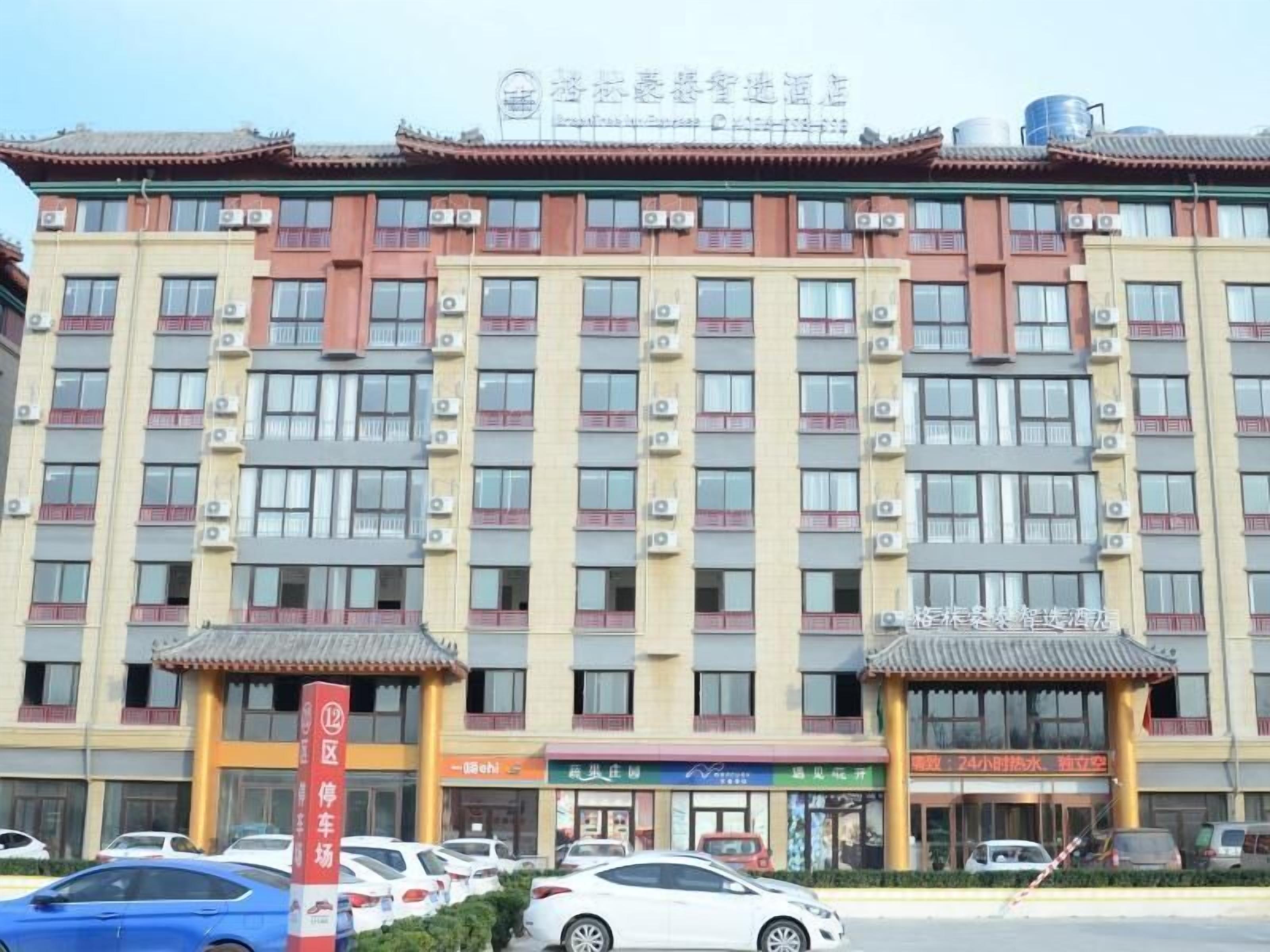 Ein mehrstöckiges Hotel mit traditioneller Architektur, Klimaanlagen und einem Parkplatz mit mehreren Autos.